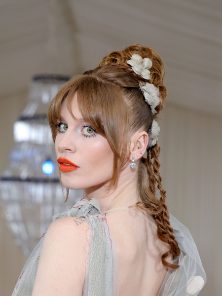 Ivy Getty with a braided ponytail orange red lipstick and statement lower lashes '70s makeup trend